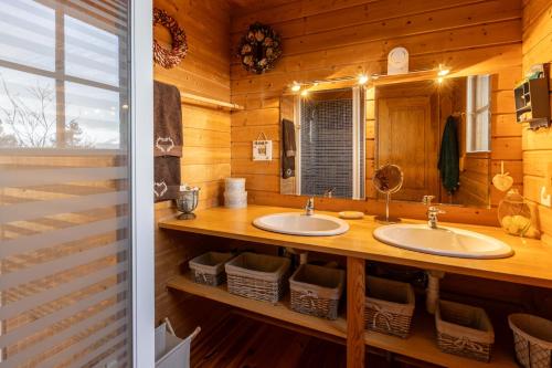 un bagno in stile baita di tronchi con 2 lavandini e uno specchio di Le Chalet des Ours - Superbe chalet 4 étoiles a Les Angles