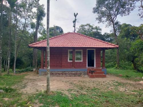 a small red house with a red roof at Nature Spot Cottages in Kurchi