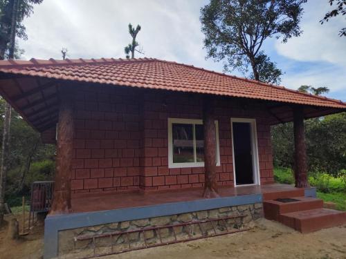 een klein huis met een rood dak bij Nature Spot Cottages in Kurchi