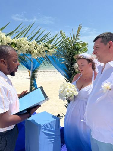 mariée et mariée sur la plage avec un homme tenant une tablette dans l'établissement Gadea Boutique Hotel& Gadea Garden Italian Restaurant, à Jambiani