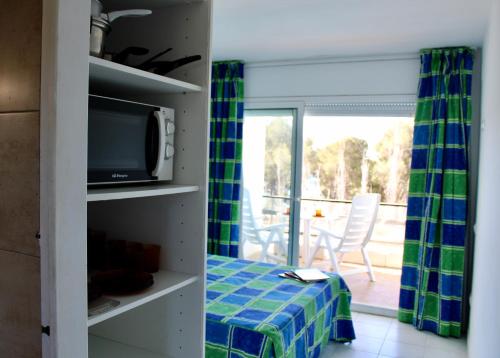 uma sala de estar com uma televisão e uma varanda em Apartamentos Cala Llevado em Tossa de Mar