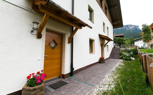 a white building with a wooden door and flowers at Appartamenti Genziana in La Villa