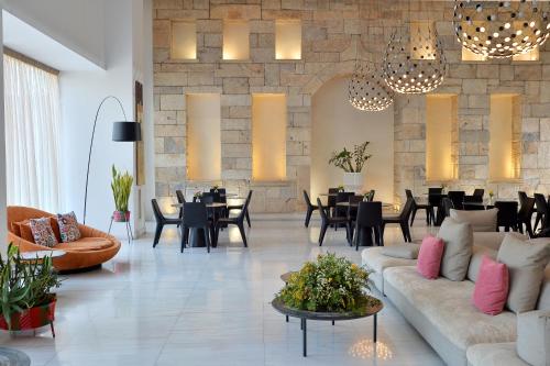 Una sala de estar con un sofá, mesas y sillas. en Athenaeum Grand Hotel, en Atenas