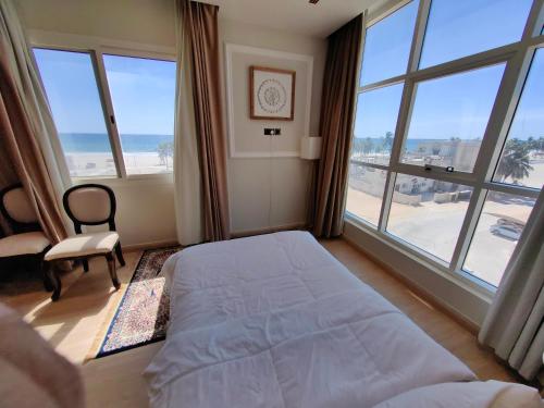 a bedroom with a bed and a large window at الشقة البحرية الدهاريز in Salalah