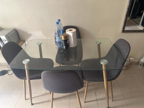 uma mesa de vidro com duas cadeiras e uma garrafa de água em De la gloire em Dakar