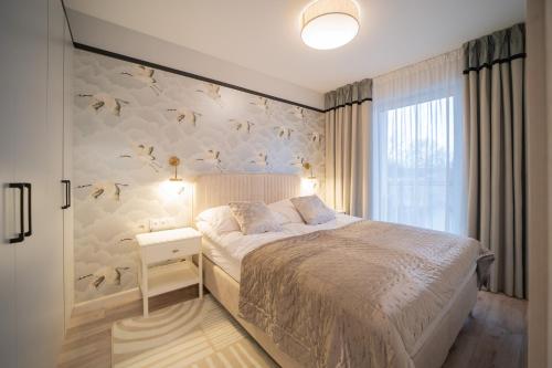 a bedroom with a bed and a wall with bird wallpaper at APARTAMENT Ceynowa in Kartuzy