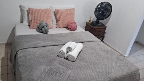 a bedroom with a bed with two towels and a fan at Chalé do riacho 1 in Itatiaia