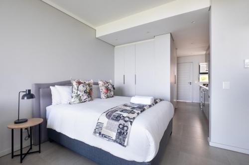 a bedroom with a large white bed and a table at The Tyne Luxury Apartments in Durban
