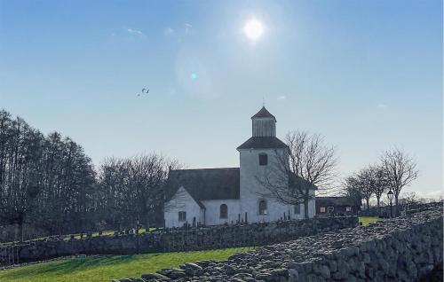 a large white church with a stone wall next to it at 2 Bedroom Nice Home In Fjälkinge in Fjälkinge