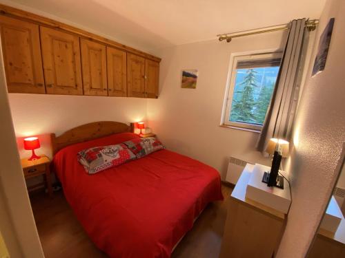 ein Schlafzimmer mit einem roten Bett und einem Fenster in der Unterkunft Appartement centre Vars les Claux 150 m des pistes in Vars