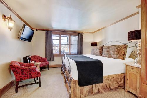 a bedroom with a bed and a chair and a television at Lodge at Vail, A RockResort in Vail
