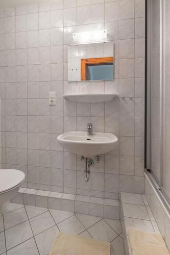 Baño blanco con lavabo y espejo en Haus Naase App 3 en Norderney