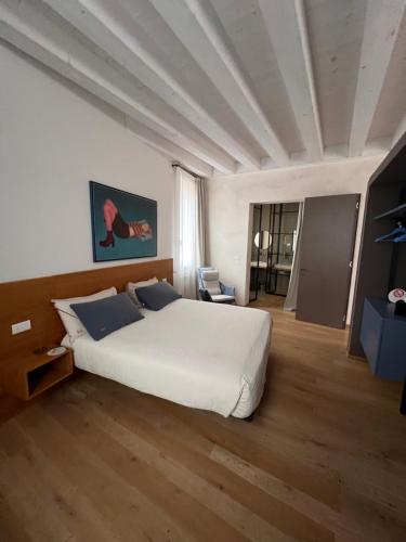 a bedroom with a large white bed and wooden floors at LEONI DI COLLALTO PALACE in Treviso
