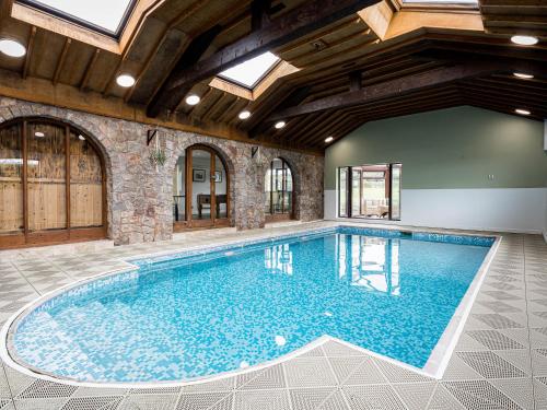 een zwembad in een huis met een plafond met ramen bij Brookway Lodge in Holywell