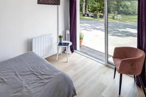 a bedroom with a bed and a chair and a sliding glass door at Propriété idéale pour coworking/voyage entreprise in Treillières