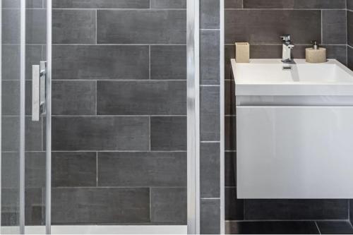 a bathroom with a sink and a tile wall at Propriété idéale pour coworking/voyage entreprise in Treillières