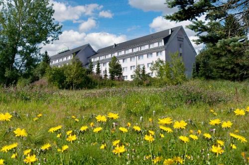 a building on a hill with a field of flowers at Aparthotel Oberhof in Oberhof