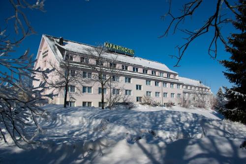 Un bâtiment avec un panneau en haut dans la neige dans l'établissement Aparthotel Oberhof, à Oberhof
