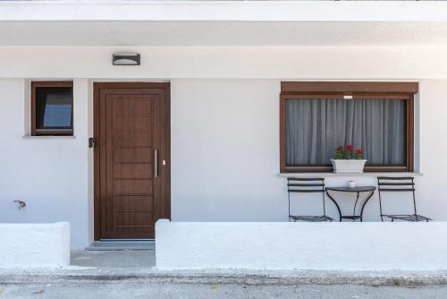 Casa blanca con mesa, sillas y puerta en ALMIRA Studios Limnos 2, en Mirina