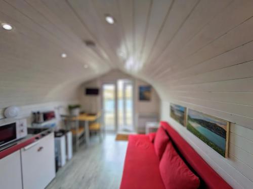 a living room with a red couch in a kitchen at Glamping Pod for 2 Pod Beag Na Haun Eriskay in Eriskay