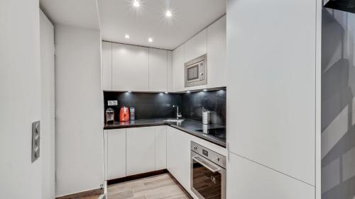 a white kitchen with white cabinets and a sink at 07 Tour Eiffel - Maison pour 5 personnes in Paris