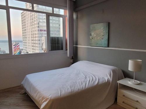 1 dormitorio con cama blanca y ventana en De frente para o Guaíba., en Porto Alegre