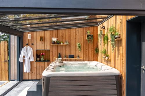 uma banheira na casa de banho com uma parede de madeira em Domaine de la Baie de Somme, suite Vanadis em Cayeux-sur-Mer