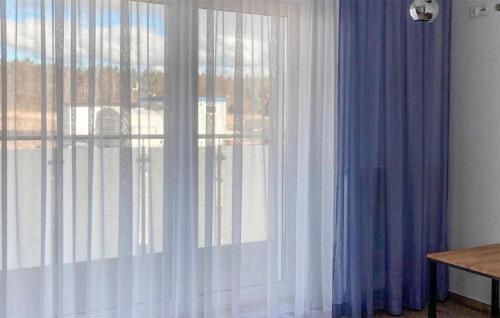 Cette chambre dispose d'une fenêtre avec des rideaux bleus et blancs. dans l'établissement Stunning Apartment In Grzybowo With Wi-fi, à Grzybowo