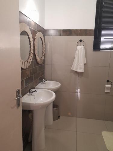 een badkamer met 2 wastafels en een spiegel bij Indaba Manor Guesthouse in Port Edward