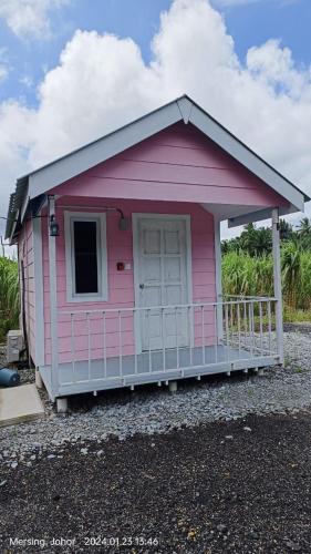 uma casa cor-de-rosa com um alpendre e uma porta em Kabin Pink em Mersing