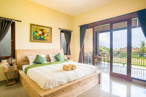 ein Schlafzimmer mit einem großen Bett und einem Balkon in der Unterkunft Greenfield Viewhouse: Spacious 2nd Floor Lodging in Ubud