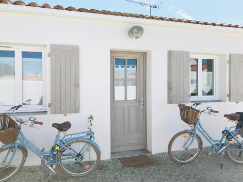 twee fietsen geparkeerd buiten een wit huis bij Boinot Lodge in Le Château-dʼOléron