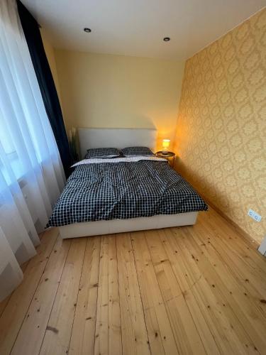 1 dormitorio con 1 cama y suelo de madera en Forentinn Kranto 43 en Panevėžys
