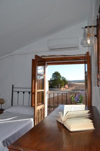 an open book on a table with a bed and a window at Casica de los Pastores in Ayora