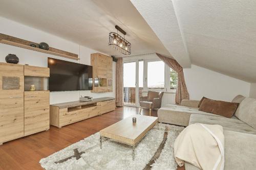 Wellness-Appartements Berchtesgadener Land في أينرينغ: غرفة معيشة مع أريكة وتلفزيون