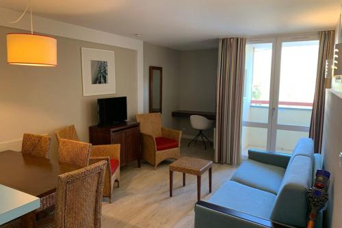 un soggiorno con un divano blu e un tavolo di Bel appartement 5 pers avec piscine tennis et parking 236 a Le Touquet-Paris-Plage
