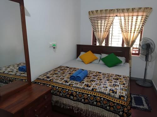 1 dormitorio con 1 cama con almohadas de colores y espejo en The Villa Hush en Hikkaduwa