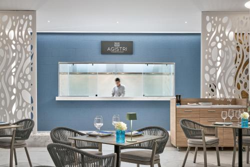 a restaurant with tables and chairs and a man in the mirror at Lindos Grand Resort & Spa - Adults Only in Líndos