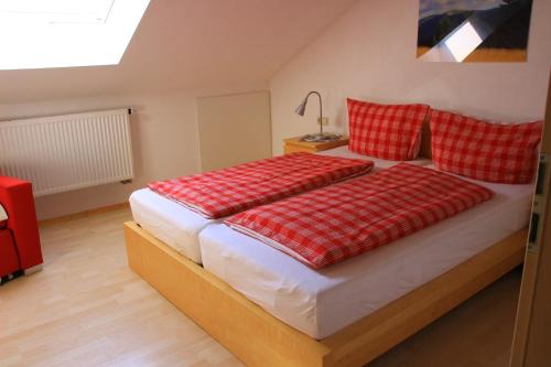 een slaapkamer met een bed met rode en witte kussens bij Sport Rees - Ferienwohnung Anna in Hofsgrund