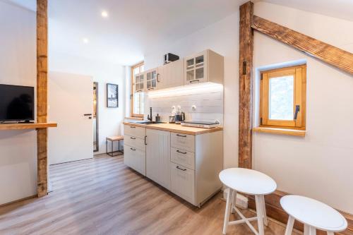 a kitchen with white cabinets and two white stools at Vila Kouty in Loučná nad Desnou