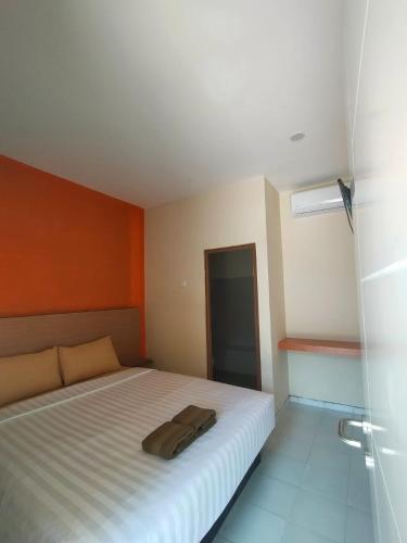een slaapkamer met een wit bed en een oranje muur bij Spazio Hotel in Karimunjawa