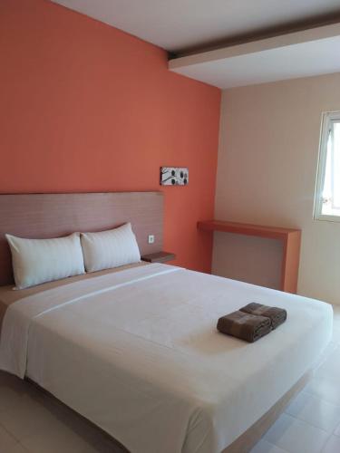 a bedroom with a large white bed with orange walls at Spazio Hotel in Karimunjawa
