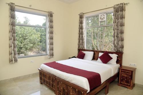 1 dormitorio con 1 cama grande y 2 ventanas en Ranthambhore Tiger Niwas, en Sawāi Mādhopur