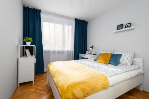 a bedroom with a large bed with blue curtains at Kairos Apartments - Spodek II - 100 m od Spodka in Katowice