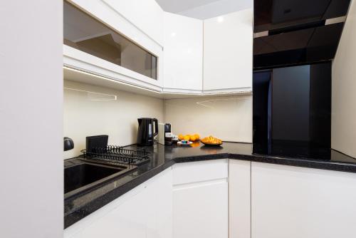 a kitchen with white cabinets and black counter tops at Kairos Apartments - Spodek II - 100 m od Spodka in Katowice