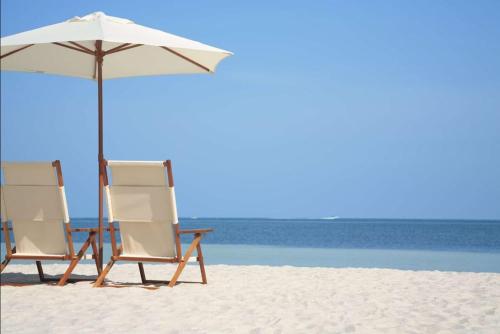 dos sillas y una sombrilla en la playa en Great Views And Just Steps to the Beach - Moonraker #31 - Sleeps 6, en Gulf Shores