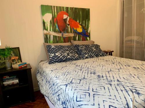 una camera da letto con un letto e un dipinto sul muro di Quarto charmoso no coração da Gavea a Rio de Janeiro