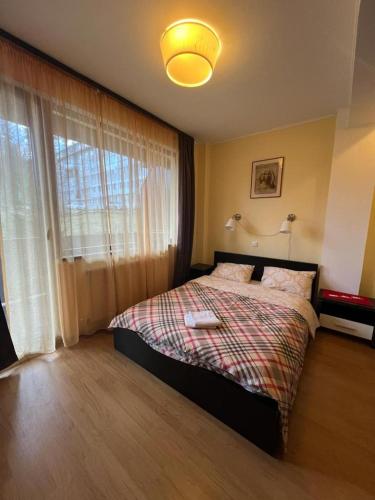 um quarto com uma cama e uma grande janela em Apartament Marcus 1 Poiana Brasov em Poiana Brasov