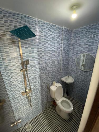 a blue tiled bathroom with a toilet and a sink at Cabuhat-Duco Lodge 3 in Naic