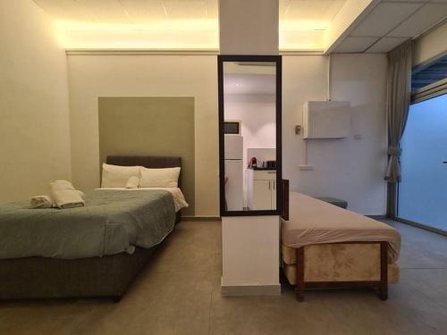 a bedroom with two beds and a mirror at White Elephant - יחידת סטודיו מקסימה צמודה לשוק מחנה יהודה in Jerusalem